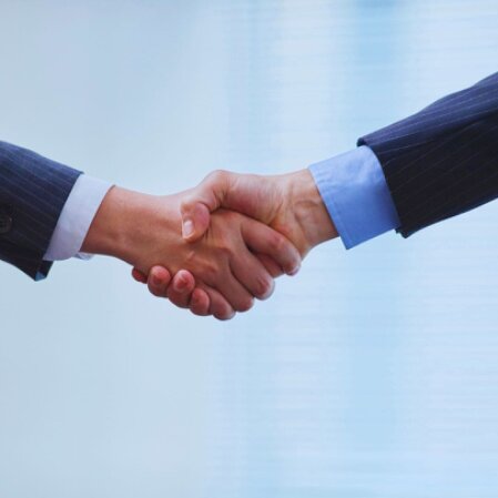 Stretta di mano tra professionisti in un contesto aziendale che rappresenta fiducia e collaborazione